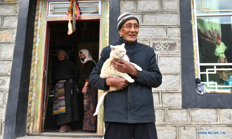 Tsering holding his cat stands in his yard in Nyinzhung Township of Damxung County, Lhasa City of southwest China's Tibet Autonomous Region, April 16, 2021.(Photo:Xinhua)