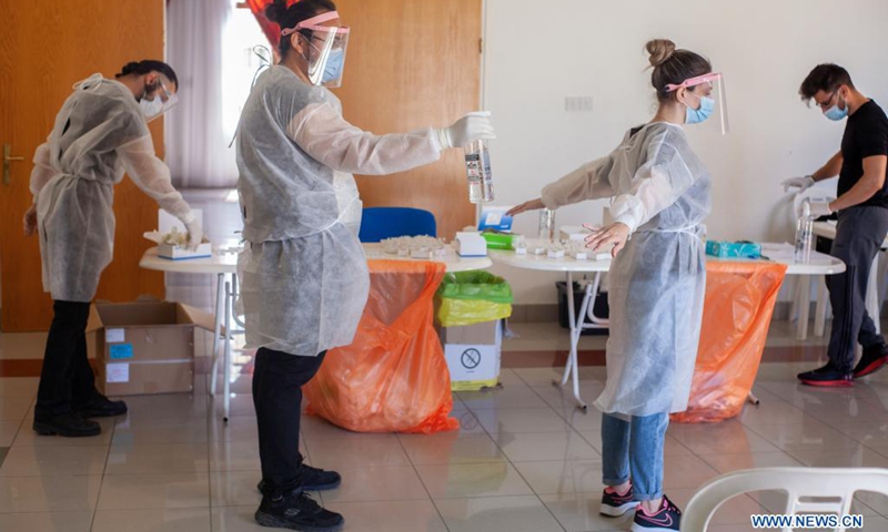 A medical worker disinfects his colleague in Nicosia, Cyprus, April 27, 2021.(Photo: Xinhua)
