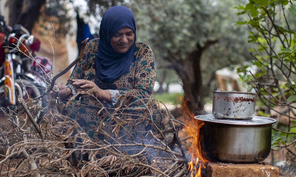 A Syrian refugee cooks food on a fire, at an informal refugee camp, in the town of Rihaniyye in the northern city of Tripoli, Lebanon, Thursday, April 8, 2021. Photo: VCG