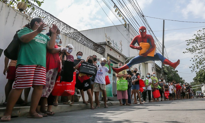 A man dressed as <em>Spider-Man</em> entertains people lining up for free goods for their children affected by the COVID-19 lockdown in Manila, the Philippines on April 27, 2021.Photo:Xinhua