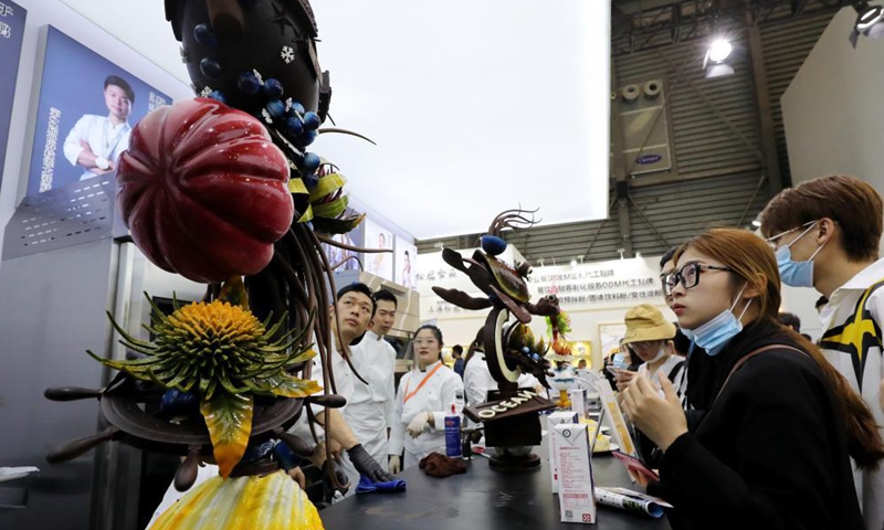 Visitors watch a collection of items made of chocolate on the Bakery China 2021 exhibition at the Shanghai New International Expo Centre in east China's Shanghai, April 27, 2021. The exhibition opened here on Tuesday where more than 2,300 exhibitors in the bakery industry showcased their products, services and technologies.Photo:Xinhua