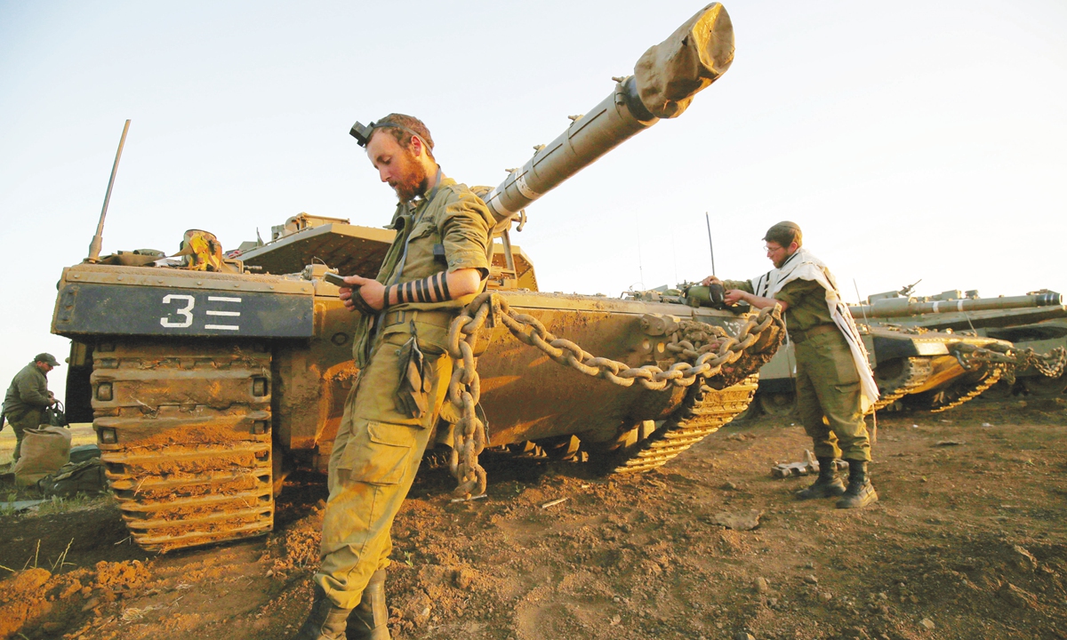Israeli soldiers pray in early morning next to Merkava Mark IV battle tanks near Moshav Alonei HaBashan in the Israeli-occupied Golan Heights on Thursday. A Syrian surface-to-air missile exploded in southern Israel on April 22, the Israeli military said, in an incident that triggered warning sirens in an area near the secretive Dimona nuclear reactor. Photo: AFP