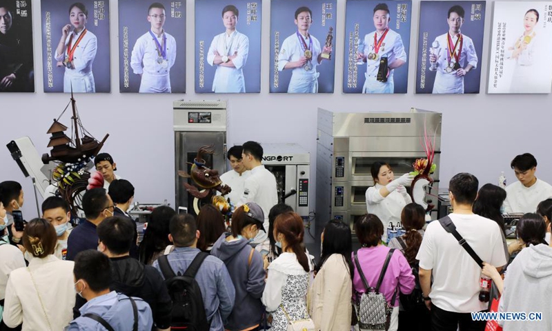 Visitors watch the making of chocolates on the Bakery China 2021 exhibition at the Shanghai New International Expo Centre in east China's Shanghai, April 27, 2021. The exhibition opened here on Tuesday where more than 2,300 exhibitors in the bakery industry showcased their products, services and technologies.Photo:Xinhua