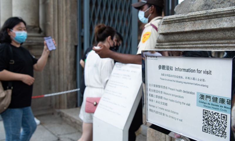 A tourist displays her Macao health code to a janitor before entering the Ruins of St. Paul's in south China's Macao, on May 3, 2021, the third day of China's five-day May Day holiday. (Xinhua/Cheong Kam Ka)