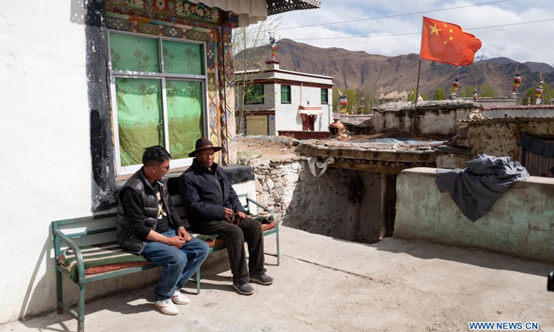 Norbu (R) talks with his son in his yard in Dagze District of Lhasa, southwest China's Tibet Autonomous Region, April 25, 2021.(Photo: Xinhua)
