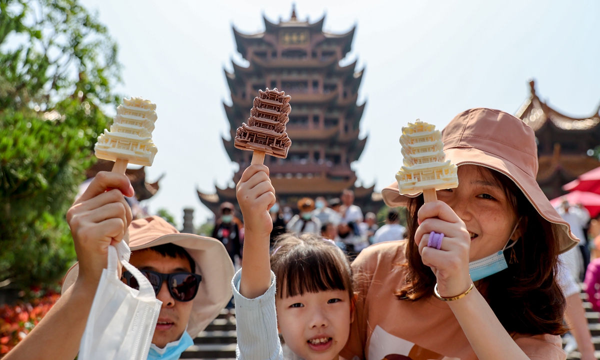 Tourists pose in front of the Yellow Crane Tower of Wuhan, Central China's Hubei Province, with specially-designed popsicles shaped exactly like the tower.
