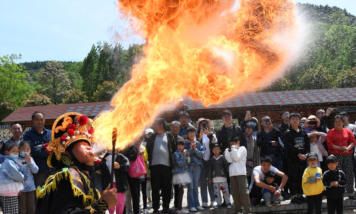 An actor gives a fire breathing performance, a trick from the Sichuan Opera, in front of tourists at Hulutao village, East China's Shandong Province on May 2. Photos: IC
