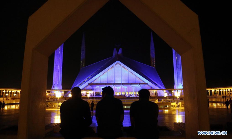 People look at the Faisal Mosque illuminated in blue in Islamabad, capital of Pakistan, on May 4, 2021. The Faisal Mosque on Tuesday was illuminated in blue to express gratitude to the frontline health workers fighting against COVID-19 in Pakistan. (Photo: Xinhua)