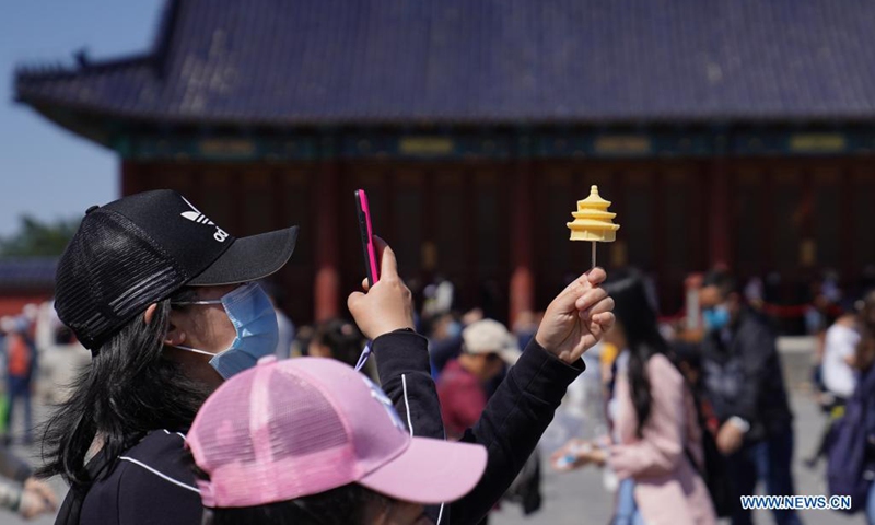 A tourist takes photos of an ice cream in the shape of the Hall of Prayer for Good Harvest at the Temple of Heaven in Beijing, capital of China, May 4, 2021. Official data showed 230 million domestic tourist trips were made during the five-day Labor Day holiday, up 119.7 percent from last year. (Photo: Xinhua)