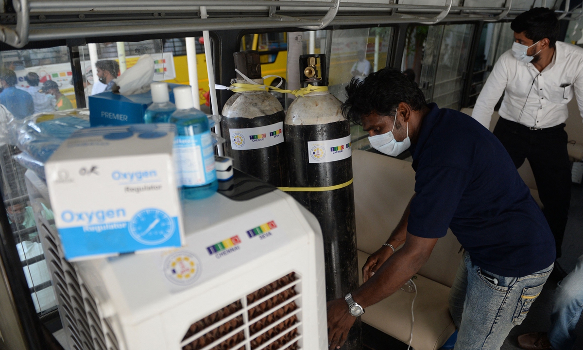 A volunteer arranges oxygen cyclinders inside a bus converted to provide oxygen to Covid-19 coronavirus patient with breathing problems while waiting to be admitted at government hospital on May 5, 2021. Photo: VCG