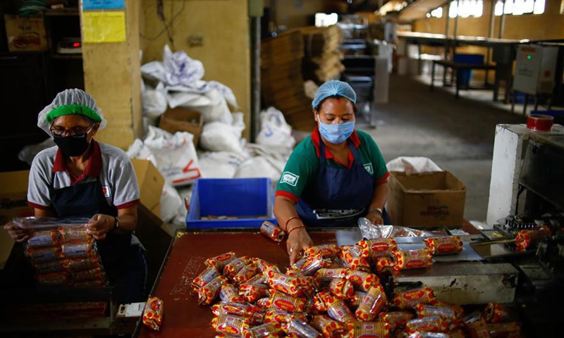 Two women work at a biscuit factory in Kathmandu, Nepal on May 8, 2020. Nepali industrialists and economists said that restoring the supply chain disturbed by the ongoing lockdown in Nepal would be crucial to resume operation of nearly four dozen sectors after the Nepali government on Wednesday relaxed the provisions of lockdown for them.Photo:Xinhua