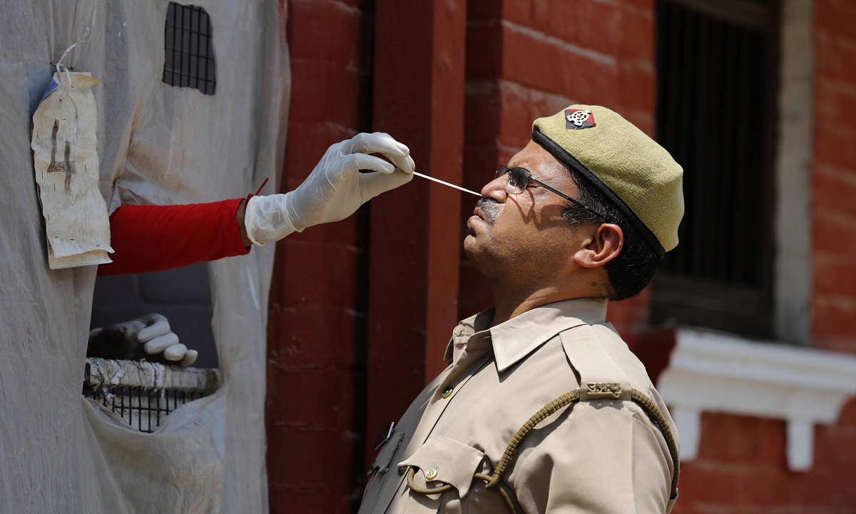 A health worker takes a nasal swab sample of a policeman to test for COVID-19 in Prayagraj, India, Saturday, May 8, 2021. Photo: VCG