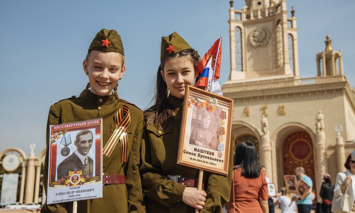 Russian girls hold up pictures of their predecessors who took part in the Great Patriotic War during the 