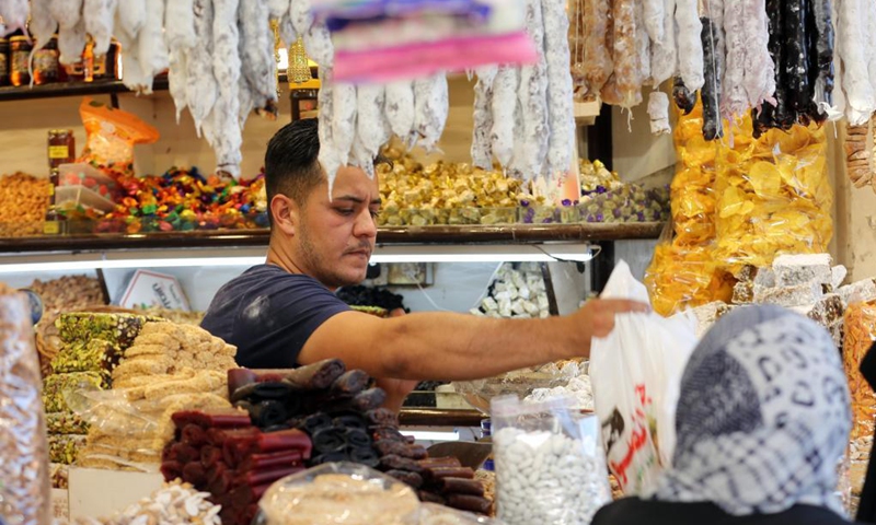 A shop owner sells dried fruits and sweets for the Eid al-Fitr in Baghdad, Iraq, on May 9, 2021. Eid al-Fitr marks the end of the Islamic holy month of Ramadan.(Photo: Xinhua)