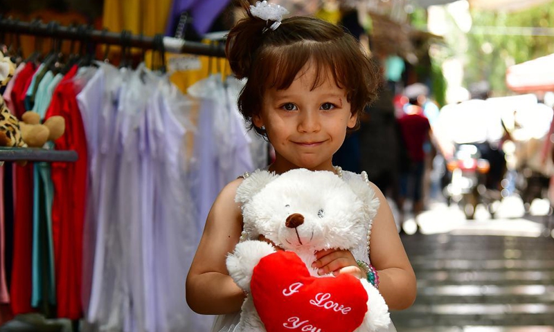 A girl poses for a photo with a teddy bear at a market in Damascus, Syria, May 11, 2021. Eid al-Fitr that marks the end of the Islamic holy month of Ramadan is approaching. Photo: Xinhua