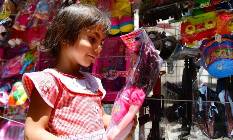 A girl picks a doll at a market in Damascus, Syria, May 11, 2021. Eid al-Fitr that marks the end of the Islamic holy month of Ramadan is approaching. Photo: Xinhua
