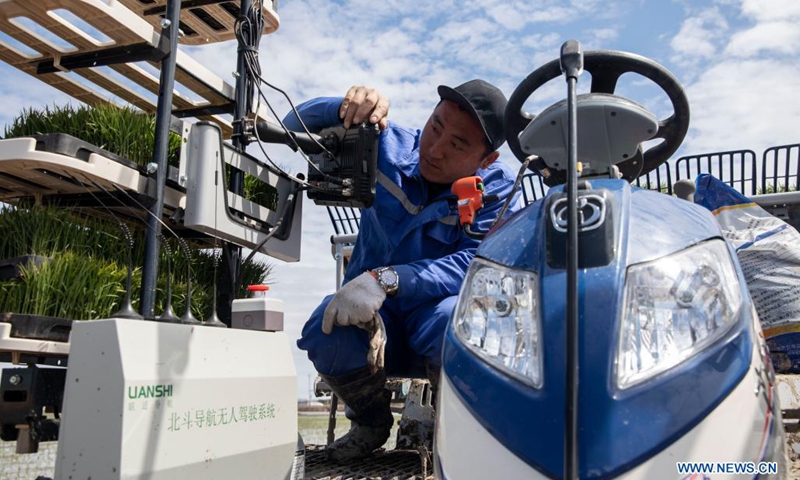 A staff member sets working route for an unmanned transplanter on a vehicle-mounted terminal tablet in a smart agriculture demonstration zone administered by Hongwei Farm Co., Ltd. of Beidahuang Group in northeast China's Heilongjiang Province, May 11, 2021. Equipped with a self-driving system based on the Beidou Navigation Satellite System (BDS), the smart transplanter can independently finish rice transplanting, avoid obstacles and turn around when needed.(Photo: Xinhua)