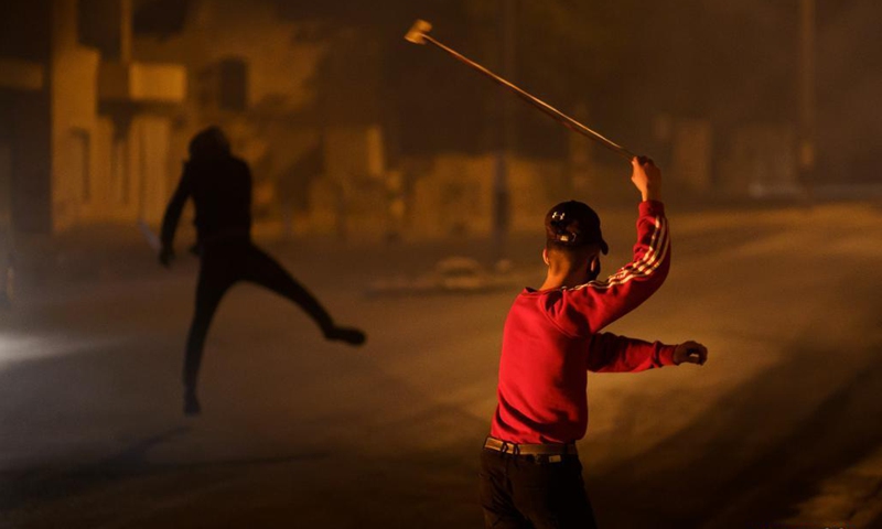 A protester hurls a stone at members of Israeli border police following an anti-Israel protest against the violence in Jerusalem, in the West Bank city of Bethlehem, on May 12, 2021. Tension between Israelis and Palestinians has been flaring up over the past few days amid the escalating violence.(Photo: Xinhua)