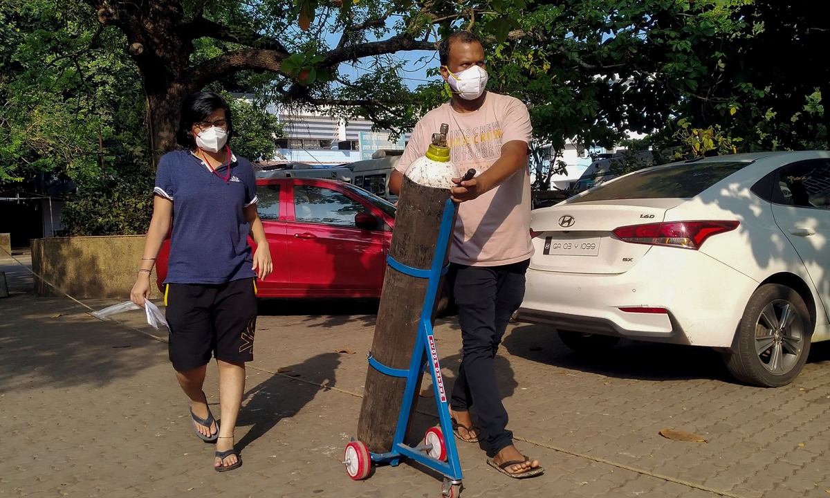 A couple walks with an oxygen cylinder for a COVID-19 coronavirus patient addmited at the Goa Medical College and Hospital (GMCH), where 26 people admitted in the hospital due to the coronavirus died on the early morning, in Panjim, India.  Photo: VCG