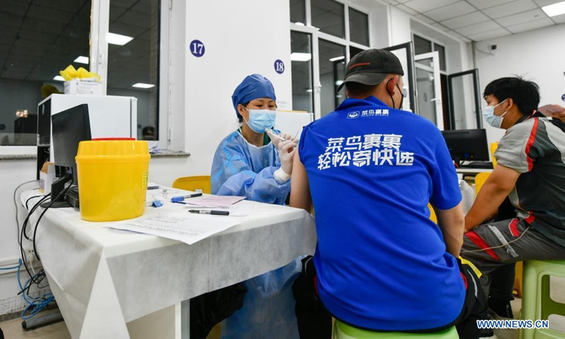 A medical worker administers a dose of COVID-19 vaccine to a courier at a vaccination site in Nankai District, north China's Tianjin, May 12, 2021. A temporary vaccination site was launched to administer the second dose of COVID-19 vaccine for more than 1,000 deliverymen at Hongqi South Road of Nankai District, north China's Tianjin. The vaccination was arranged at night, in order not to affect the couriers' delivery work during the daytime.Photo:Xinhua