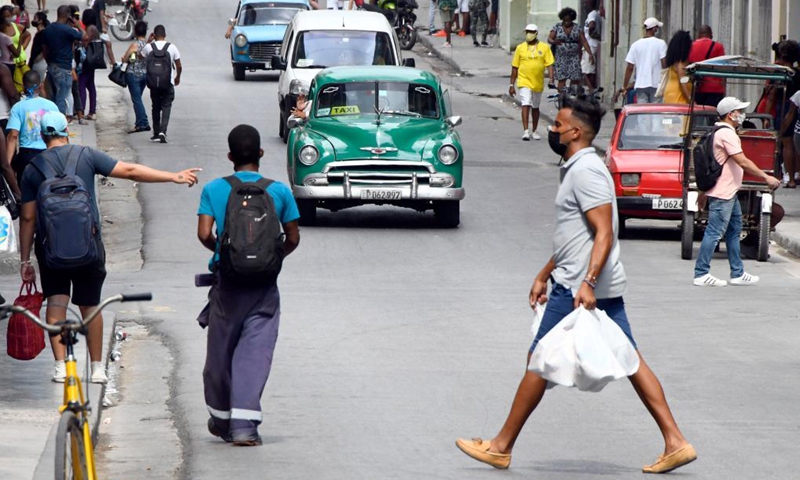 People wearing face masks walk on a street in Havana, Cuba, May 13, 2021. New variants of the coronavirus believed to have entered Cuba in recent months have been linked to higher transmission rates, more severe cases of disease and an increase in deaths in the Caribbean country, the official daily Granma said on Thursday.Photo:Xinhua
