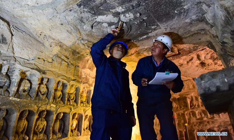 Sun Bo (L), a technician with the Yungang Grottoes Research Institute, maintains a piece of relics at the Yungang Grottoes in Datong, north China's Shanxi Province, on May 7, 2021.Photo:Xinhua