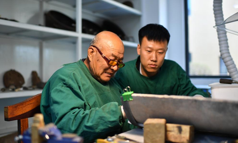 He Yu (R), a technician with the Yungang Grottoes Research Institute, learns to restore a piece of relics from a senior colleague in his studio in Datong, north China's Shanxi Province, on May 8, 2021.Photo:Xinhua