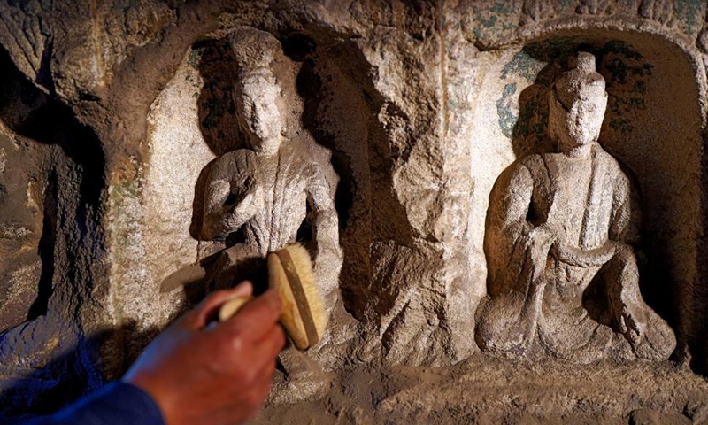 Sun Bo, a technician with the Yungang Grottoes Research Institute, maintains a piece of relics at the Yungang Grottoes in Datong, north China's Shanxi Province, on May 7, 2021.Photo:Xinhua