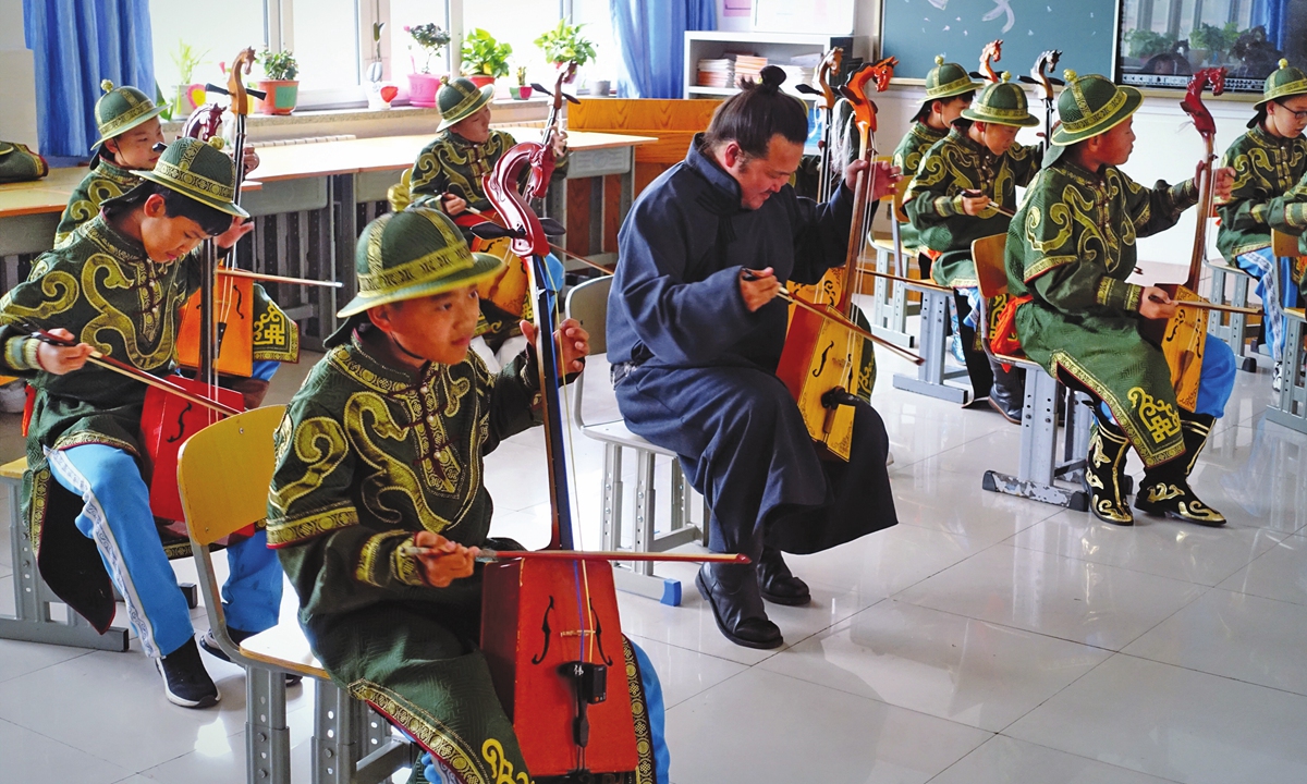  Students play the horse head fiddle with their teacher who comes from the grassland on Friday. Photo: Lin Xiaoyi/GT
