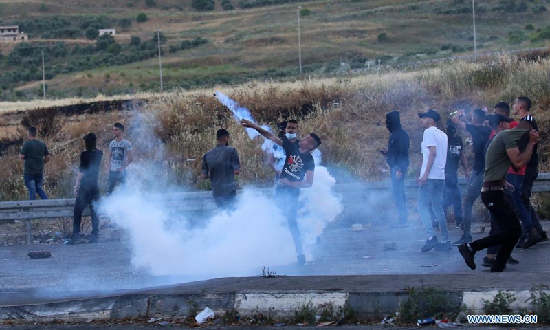 A protester throws back a tear gas canister fired by Israeli soldiers during an anti-Israel protest at Huwwara checkpoint near the West Bank city of Nablus, on May 15, 2021. The tension between Israelis and Palestinians has been flaring up over the past few days amid the escalating violence in East Jerusalem between Palestinian demonstrators and Israeli forces.(Photo: Xinhua)