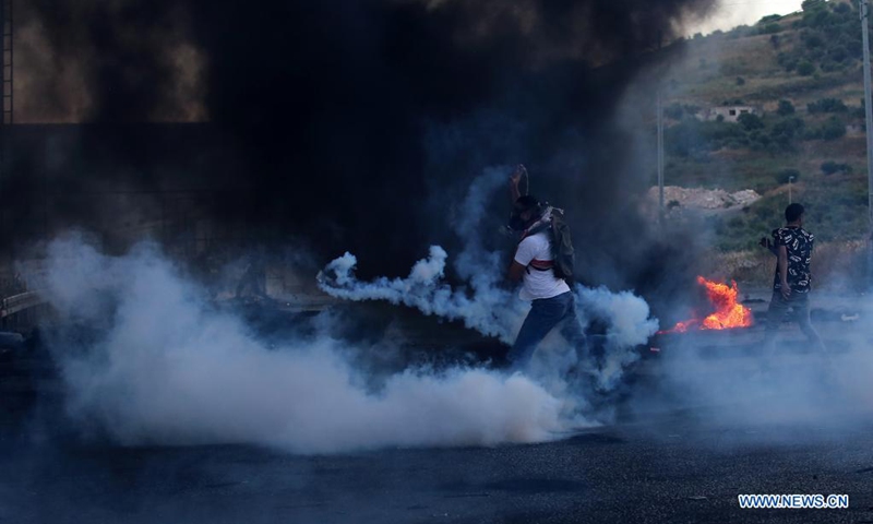A protester throws back a tear gas canister fired by Israeli soldiers during an anti-Israel protest at Huwwara checkpoint near the West Bank city of Nablus, on May 15, 2021. The tension between Israelis and Palestinians has been flaring up over the past few days amid the escalating violence in East Jerusalem between Palestinian demonstrators and Israeli forces.(Photo: Xinhua)