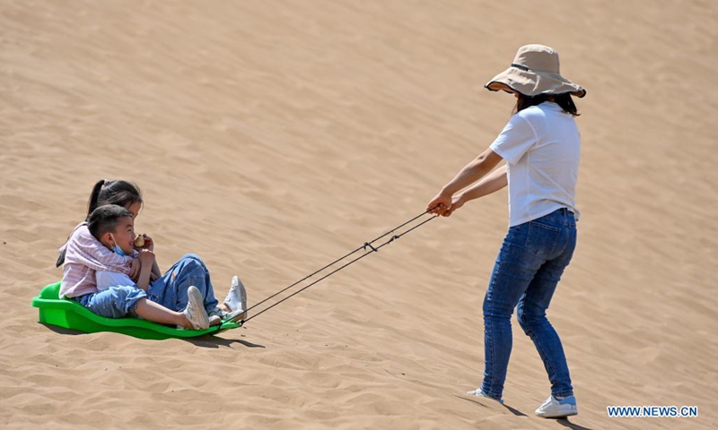 Visitors experience sand sliding in Kumtag Desert in Shanshan County, northwest China's Xinjiang Uygur Autonomous Region, May 15, 2021. The county sees boom in desert tourism early May.(Photo: Xinhua)