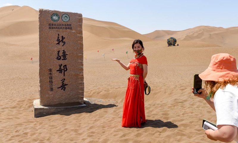 A visitor poses for photos in Kumtag Desert in Shanshan County, northwest China's Xinjiang Uygur Autonomous Region, May 15, 2021. The county sees boom in desert tourism early May.(Photo: Xinhua)