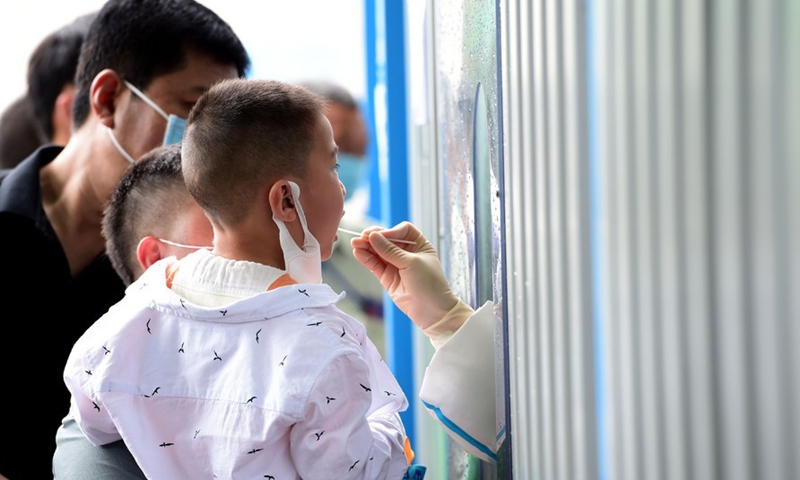 A medical worker collects a swab sample from a child for nucleic acid testing at a hospital in Feixi County of east China' Anhui Province, May 15, 2021.(Photo:Xinhua)