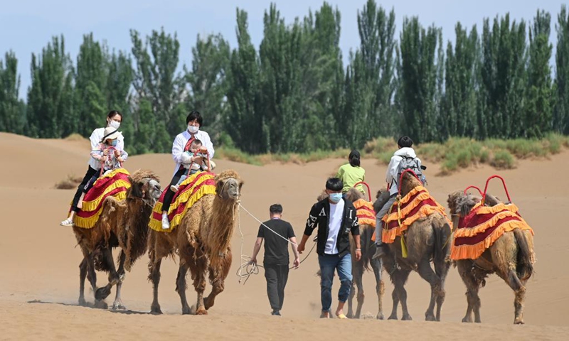 Visitors ride camels in Kumtag Desert in Shanshan County, northwest China's Xinjiang Uygur Autonomous Region, May 16, 2021. The county sees boom in desert tourism early May.(Photo: Xinhua)