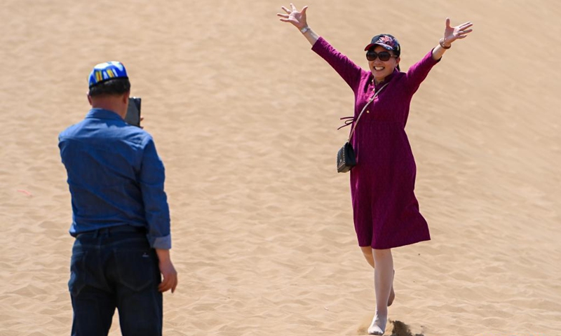 A tourist poses for photos in Kumtag Desert in Shanshan County, northwest China's Xinjiang Uygur Autonomous Region, May 15, 2021. The county sees boom in desert tourism early May.(Photo: Xinhua)