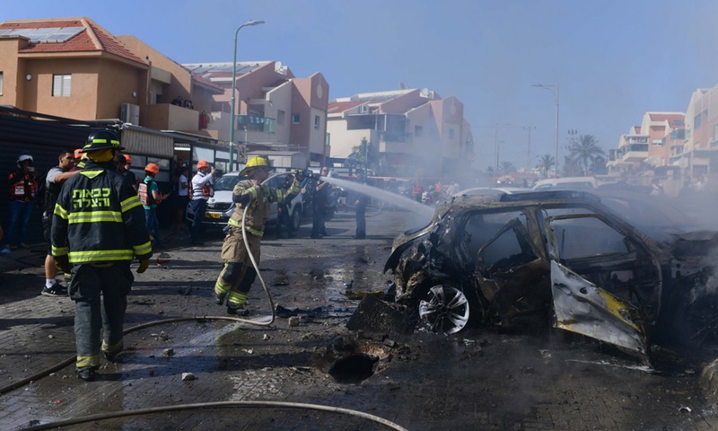 A firefighter tries to extinguish fire on a burning vehicle, which was hit by a rocket fired from the Gaza strip, in southern Israeli city of Ashkelon on May 16, 2021.(Photo: Xinhua)