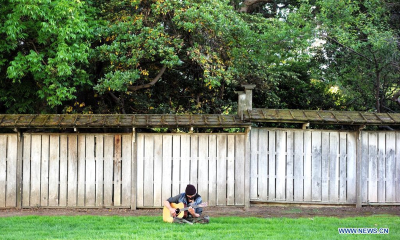 A man wearing a mask plays guitar at a park in San Mateo, California, the United States, May 17, 2021. California's public health officials said Monday the most populous state of the United States would not implement the CDC guidelines that allow fully vaccinated people to go without a mask in most situations before June 15.(Photo: Xinhua)