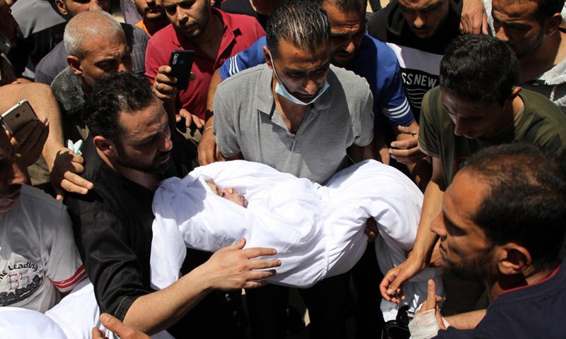 A Palestinian holds the body of a child who was killed during Israeli airstrikes on their houses, during a funeral in Gaza City, May 16, 2021.(Photo: Xinhua)