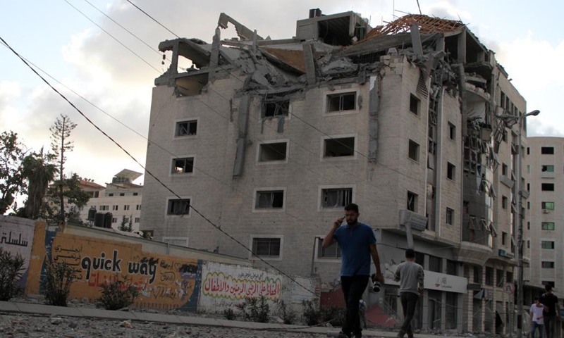 People walk past a damaged building after an Israeli air strike in Gaza City, on May 17, 2021. The intense fighting between Israel and Gaza's ruler Hamas killed 204 Palestinians, including 59 children, and 10 Israelis, including a five-year-old boy and a soldier.(Photo: Xinhua)