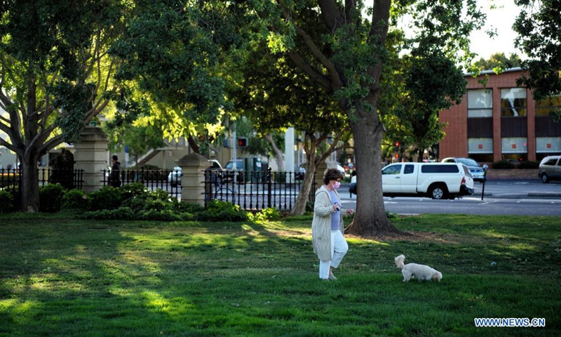 A woman wearing a mask walks a dog at a park in San Mateo, California, the United States, May 17, 2021. California's public health officials said Monday the most populous state of the United States would not implement the CDC guidelines that allow fully vaccinated people to go without a mask in most situations before June 15.(Photo: Xinhua)