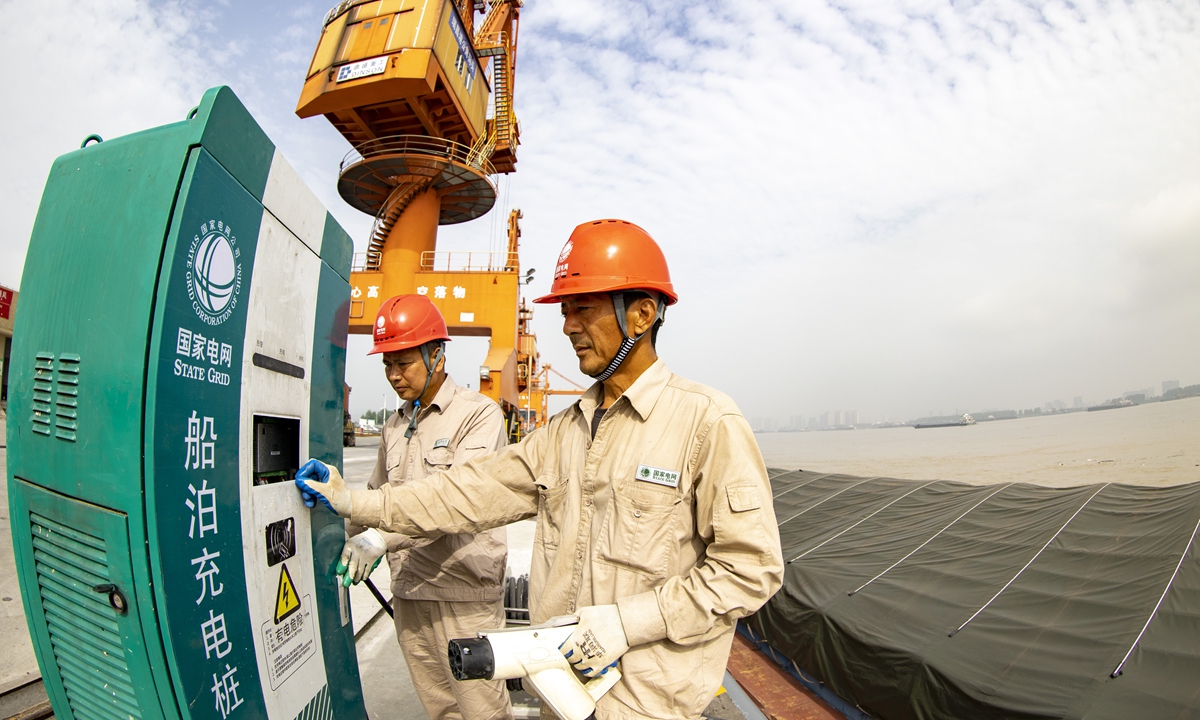Workers from the State Grid Corp of China help a barge to plug in to a charging pole built at a public wharf along the Yangtze River in East China's Jiangxi Province on Thursday. River transport electrification is going full throttle in Ruichang, Jiangxi Province with 46 sets of riverbank charging poles for ships installed at all of the city's 13 wharves. Photo: VCG