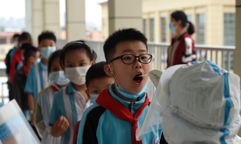 A medical worker collects a swab sample of a student for nucleic acid testing at a primary school in Lu'an, east China's Anhui Province, May 17, 2021.(Photo: Xinhua)