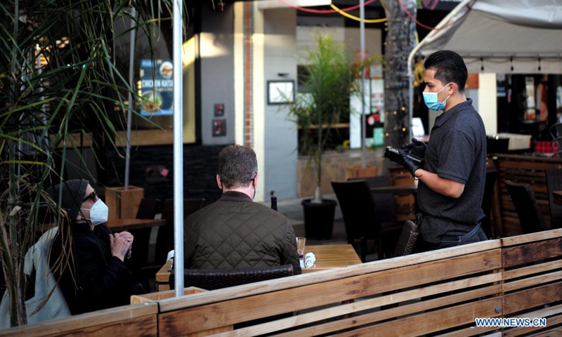 A staff member wearing a mask serves the customers at a restaurant in San Mateo, California, the United States, May 17, 2021. California's public health officials said Monday the most populous state of the United States would not implement the CDC guidelines that allow fully vaccinated people to go without a mask in most situations before June 15.(Photo: Xinhua)