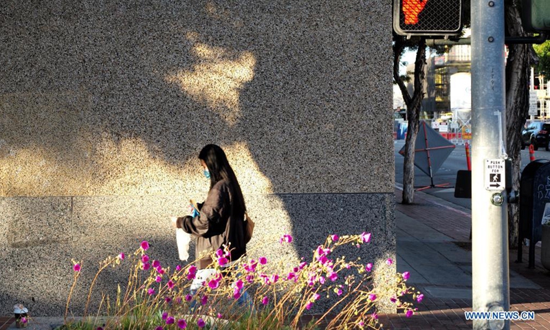 A young woman wearing a mask walks on the street in San Mateo, California, the United States, May 17, 2021. California's public health officials said Monday the most populous state of the United States would not implement the CDC guidelines that allow fully vaccinated people to go without a mask in most situations before June 15.(Photo: Xinhua)