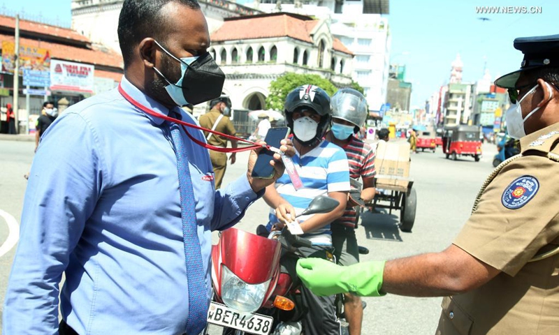 A police officer checks identification cards as authorities impose an identification card system to restrict movement of people in the face of a third wave of COVID-19 in Colombo, Sri Lanka, May 17, 2021. (Photo: Xinhua)