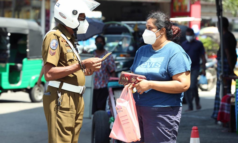 A police officer checks identification cards as authorities impose an identification card system to restrict movement of people in the face of a third wave of COVID-19 in Colombo, Sri Lanka, May 17, 2021. (Photo: Xinhua)