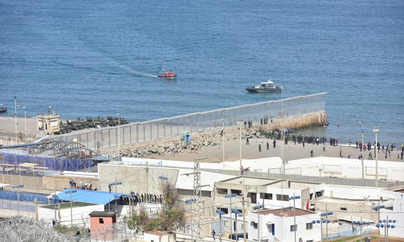 Potential migrants stand on the Moroccan side of the fence that separates the Spanish enclave from Morocco, in Fnideq, Morocco, on May 18, 2021. The Spanish enclave of Ceuta is having to deal with an influx of immigrants after an estimated 6,000 people have entered the territory from Morocco, according to the central government's delegation in the city. Photo:Xinhua