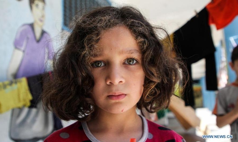 Palestinian girl Sama Al-Sultan poses for a photo at a school in Gaza City, on May 19, 2021. Al-Sultan, 5 years old, who fled her home after it was damaged during Israeli air strikes, takes refuge at the school as many other Palestinians.(Photo: Xinhua)