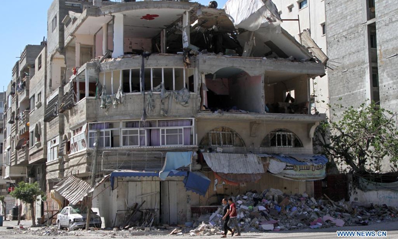 Palestinians walk past a destroyed building after an Israeli air strike in Gaza City, on May 19, 2021.(Photo: Xinhua)